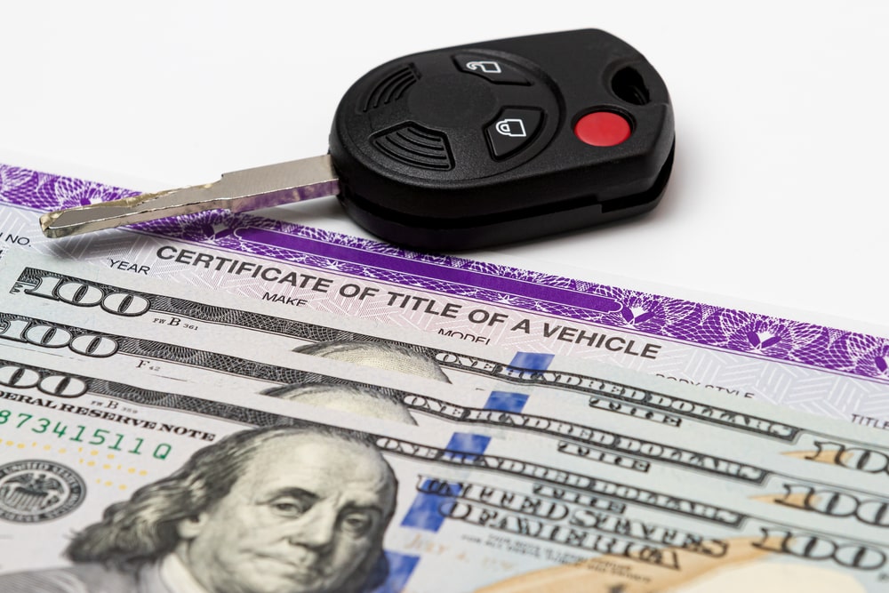 document for certificate of title for vehicle, with car keys and cash for visuals